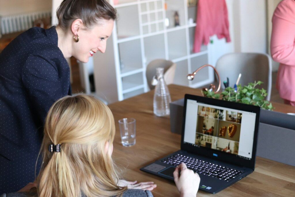 Két nő közösen dolgozik egy laptop előtt egy világos irodában, amely a magán angol tanár támogató mentori szerepét és a személyre szabott, közös fejlődés élményét szimbolizálja.